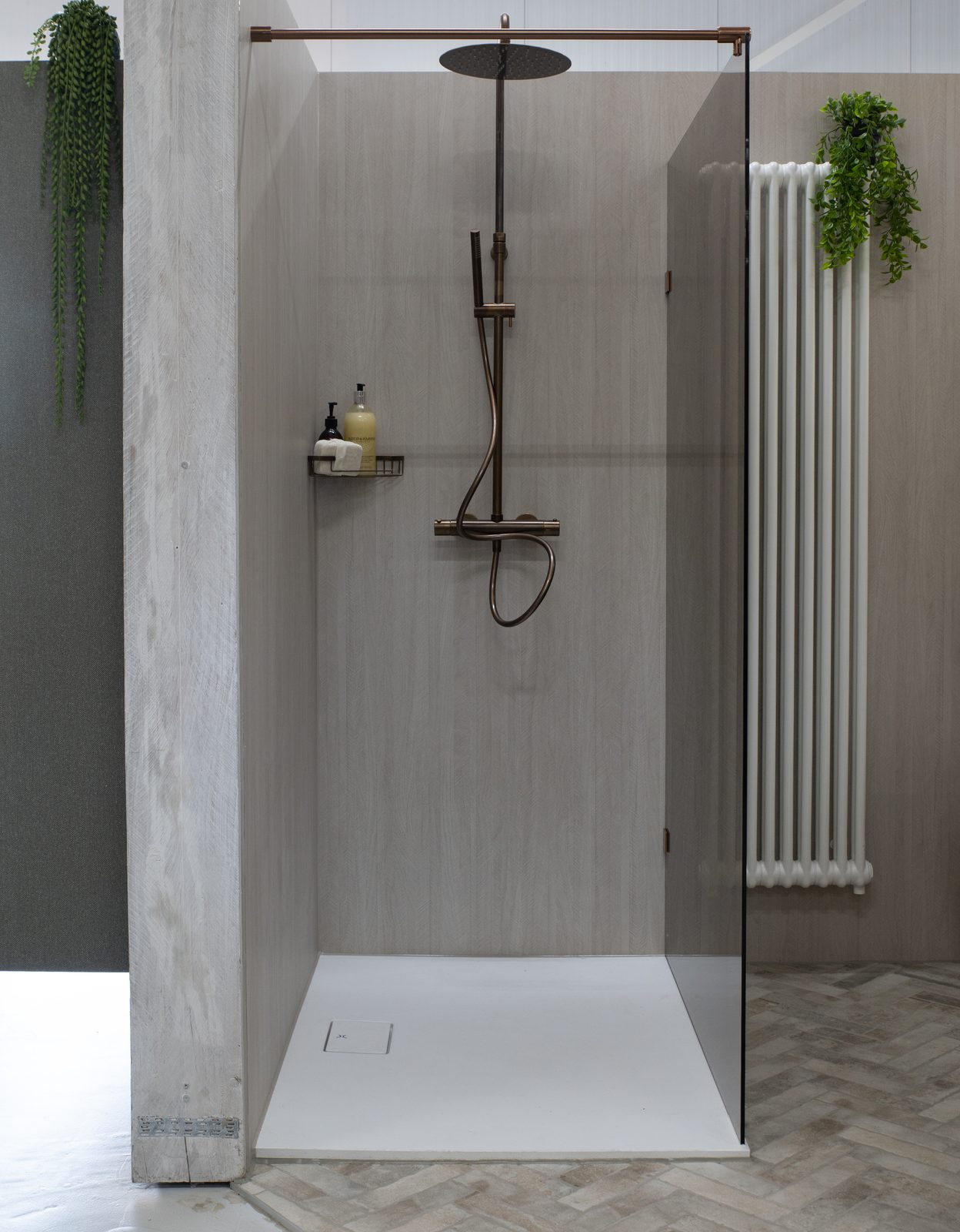 Open douche met een glaspaneel zonder profiel, bronzen doucheset en een witte douchebak