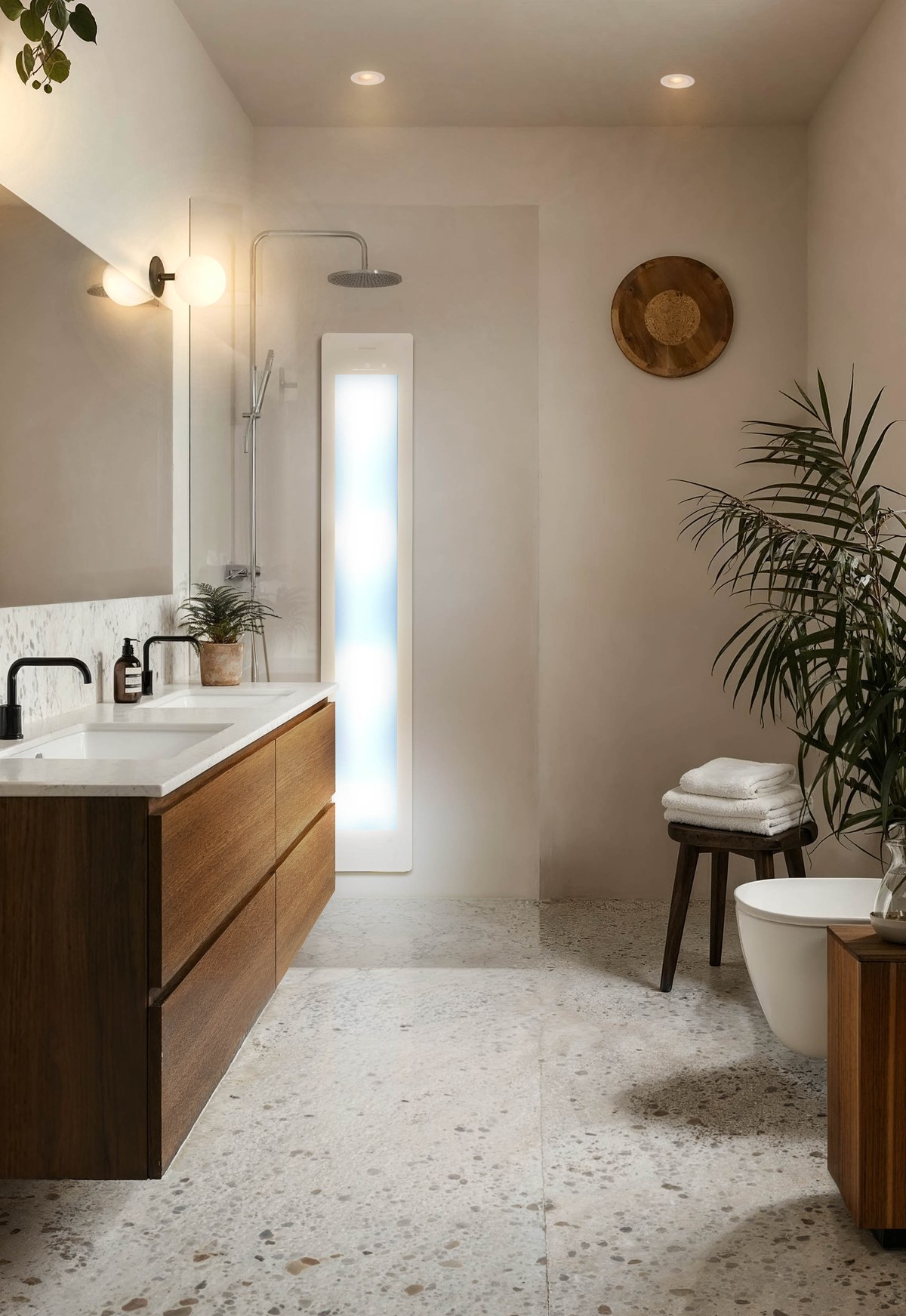 Verlicht sunshowerpaneel naast een regendouche in een lichte badkamer met terrazzovloer