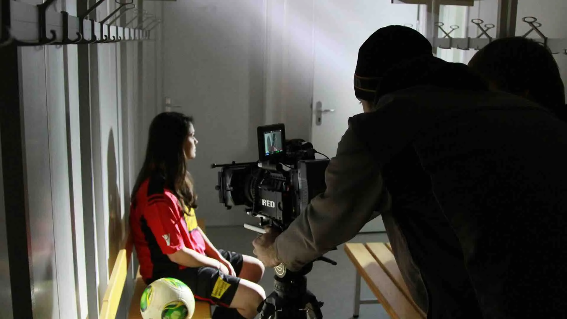 Kameramann filmt eine Fussballerin in der Umkleidekabine