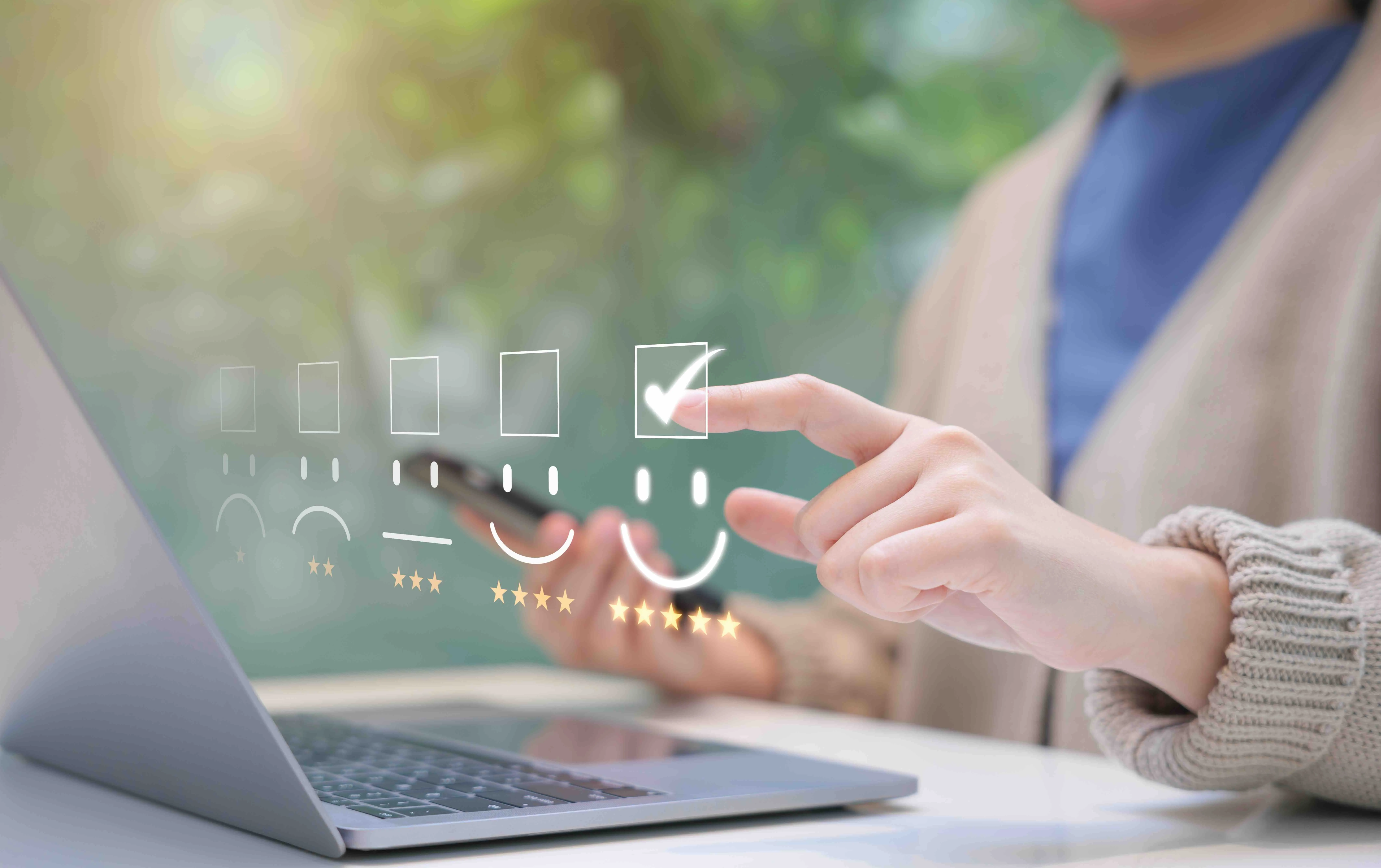 Person rating with a five-star smiley feedback system on a transparent screen over a laptop keyboard.