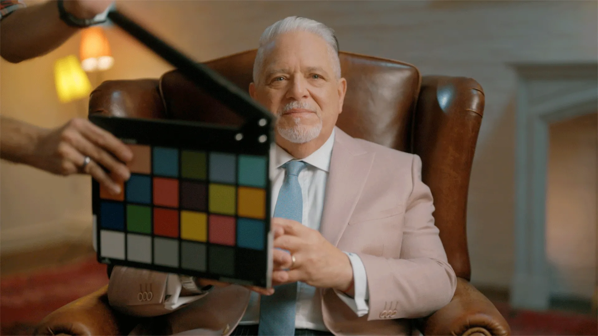 Ein Mann sitzt in einem Stuhl. Eine Filmklappe wird vor ihm gehalten.