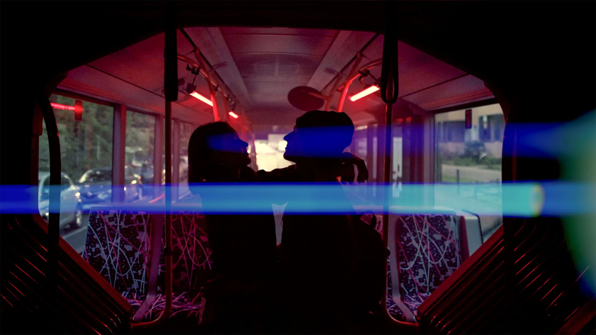 Silhouetten eines Paares, das sich in einem Bus mit roter Beleuchtung gegenübersteht und umarmt.