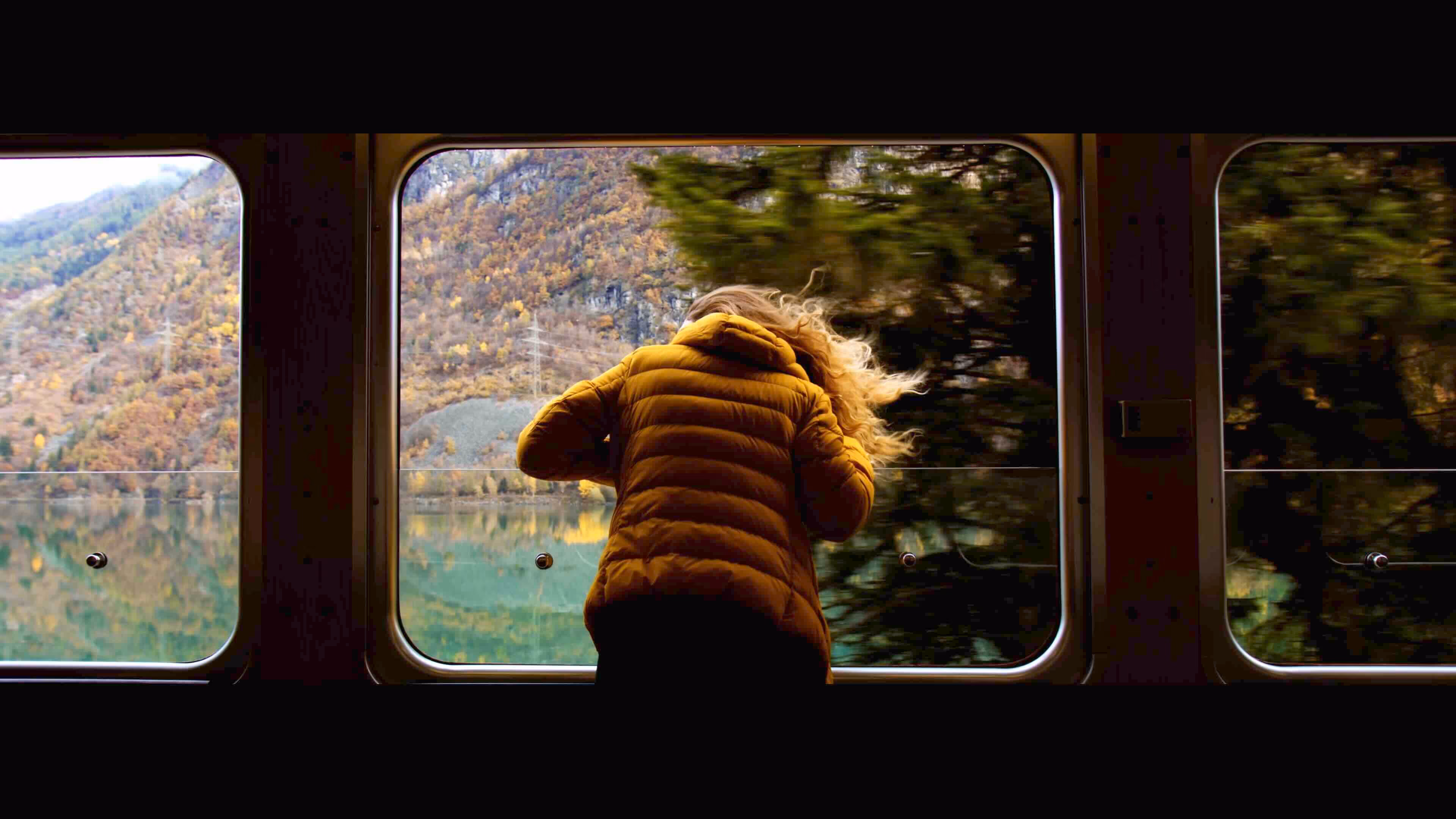 Eine Frau streckt ihren Kopf aus einem Fenster eines fahrenden Waggons.