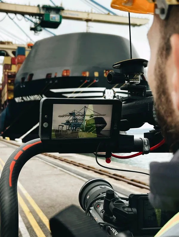 Cameraman films an MSC container ship in port during an international promotional film production.