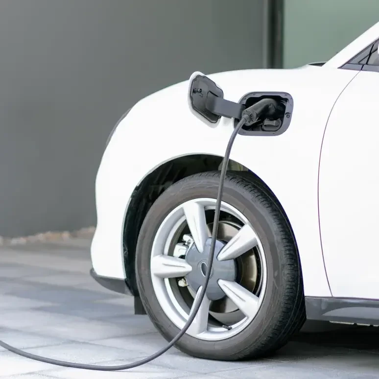 White electric car (EV) being charged at a charging station powered by sustainable and clean energy.