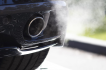 Visible fumes from a car exhaust highlight the impact of emissions, which can be reduced by transitioning to a lower emission vehicle.