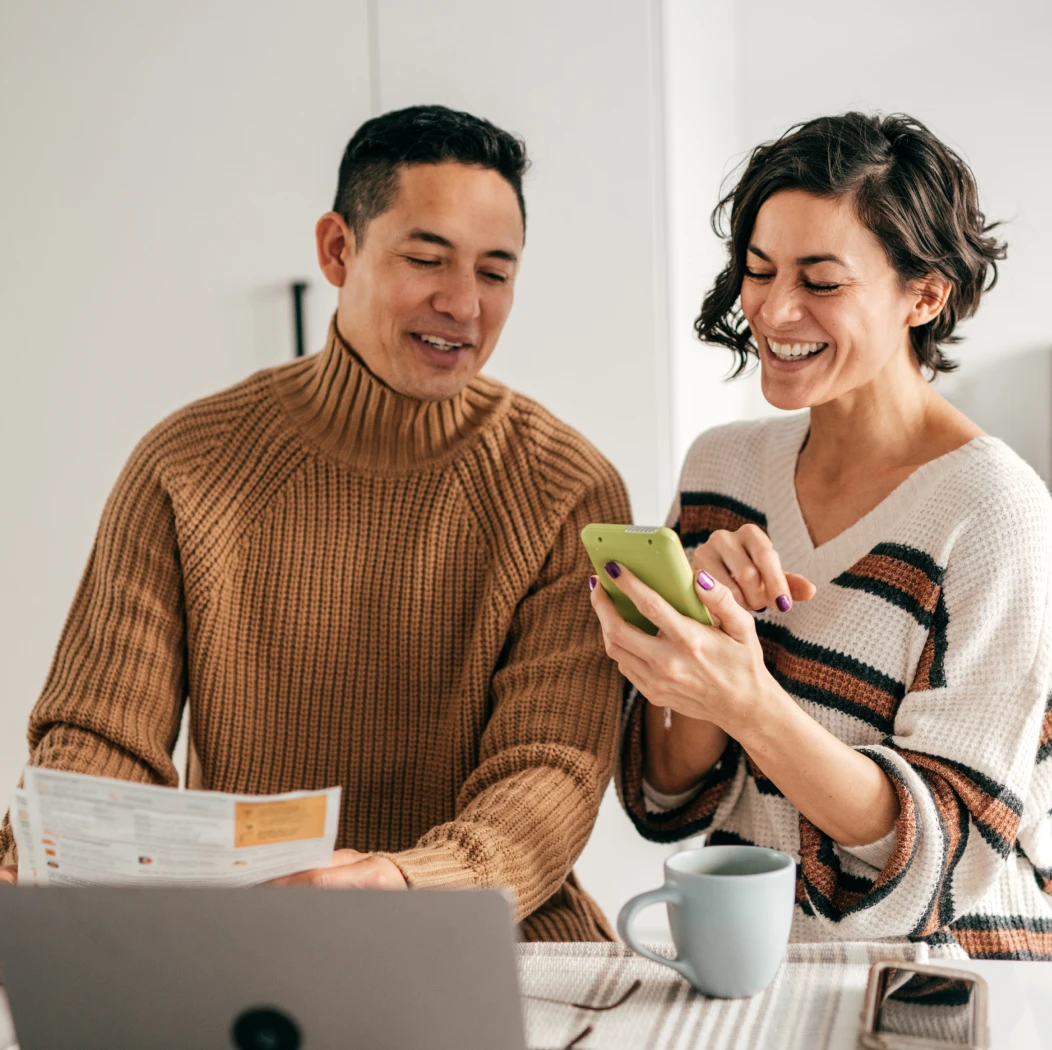 A young couple in the kitchen managing their finances and considering greener home improvements through their Tandem app.