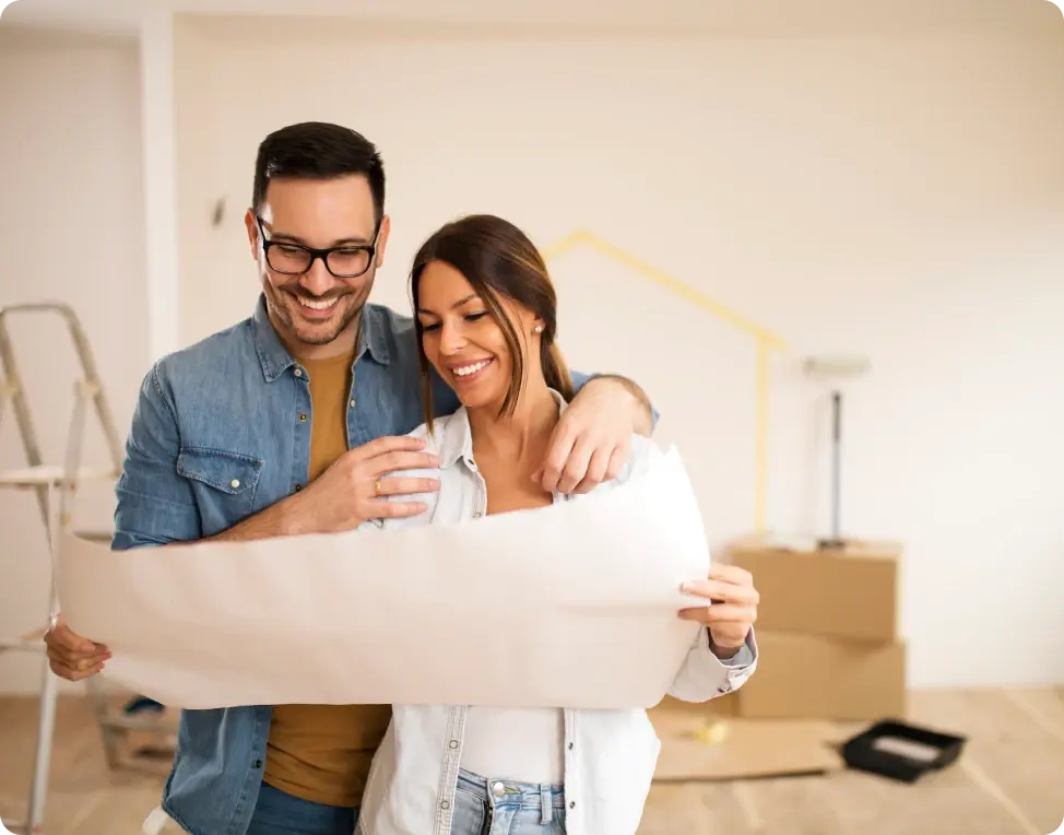 A young adult couple standing in their new home, looking at house renovation plans that were made possible with a Tandem Home Loan.