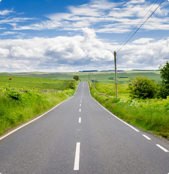 Looking directly down a UK country road, surrounded by greenery.