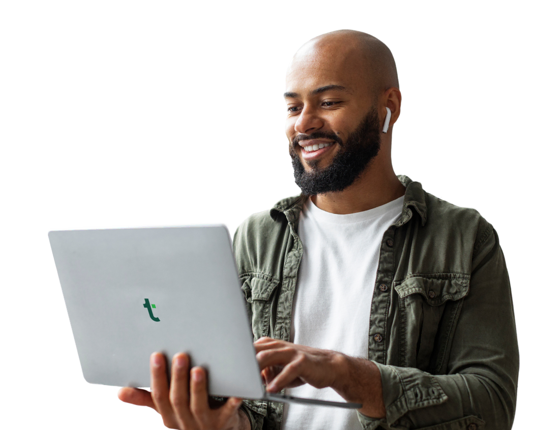 A young man wearing wireless earphones while working on his laptop, embracing Tandem's hybrid and remote working options.