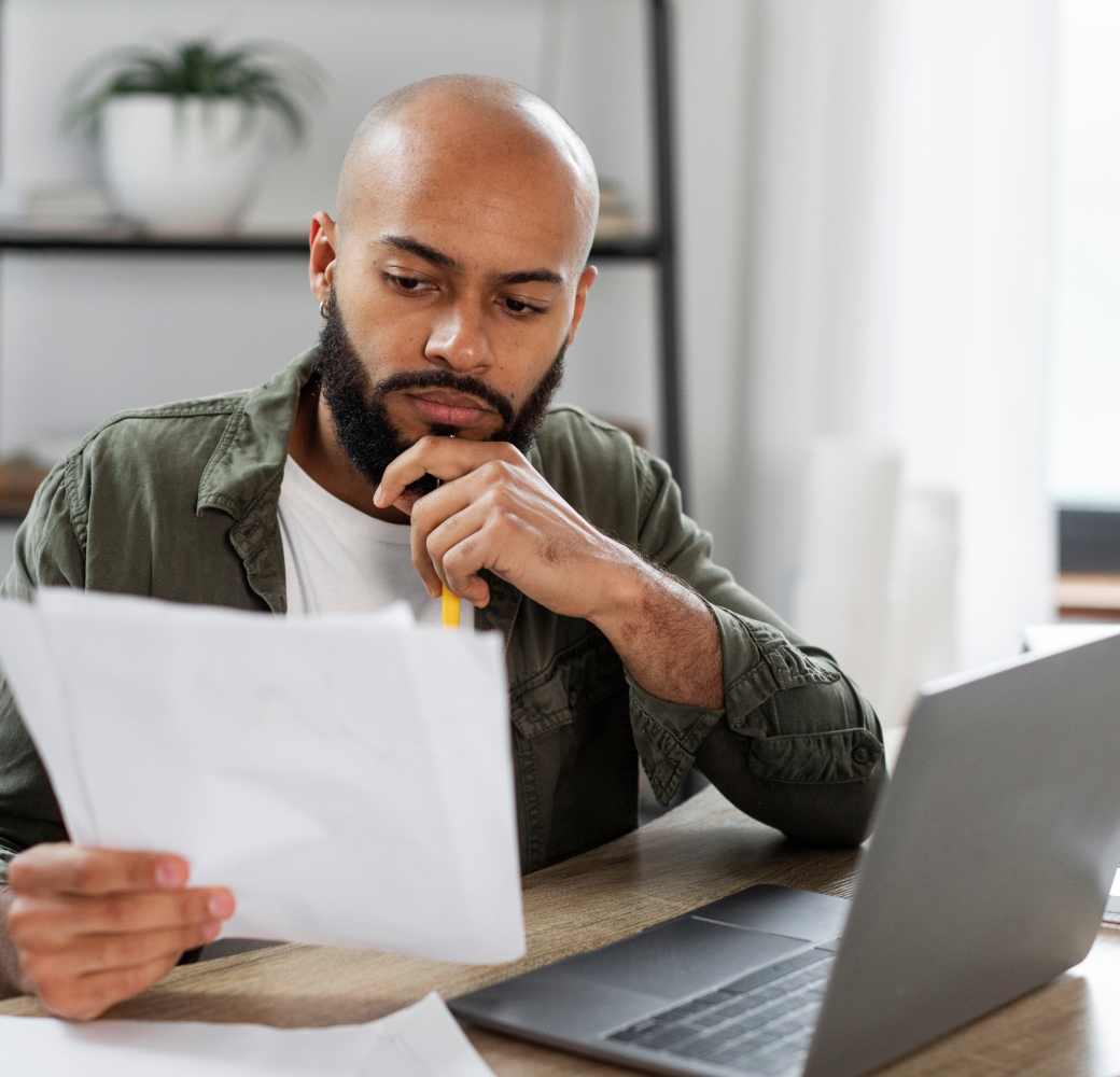 A thoughtful young man examines a sheet of paper adorned with questions he's penned, preparing to seek guidance from a Tandem customer support agent regarding his loan repayment options.