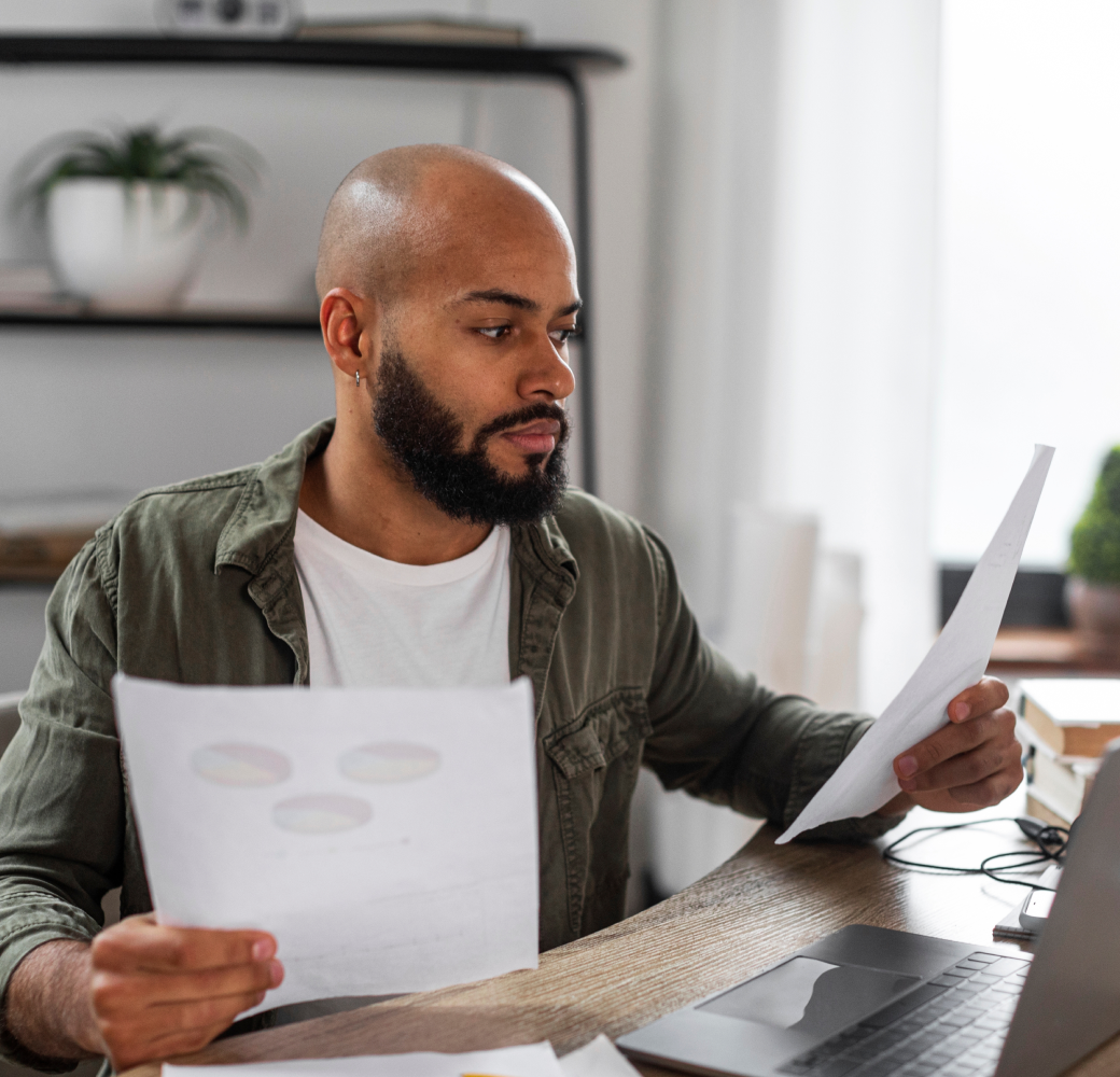 A young man diligently collects details about his loan, balances, and a budget planner, preparing to speak with a Tandem customer support representative regarding his financial situation.