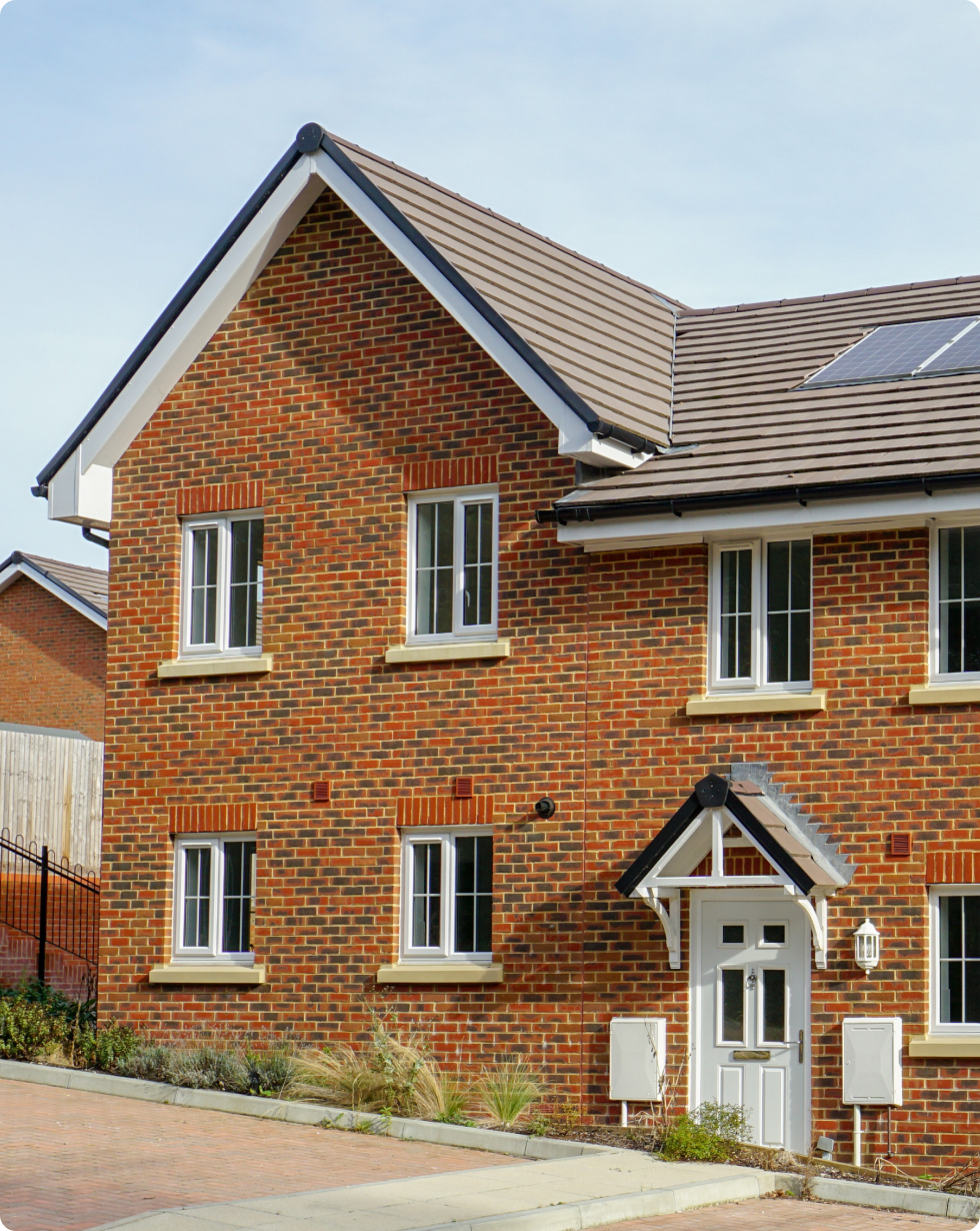 The exterior of a classic orange brick UK house showcases solar panels adorning the roof, a clear enhancement to the household's energy efficiency, resulting in significantly reduced bills.