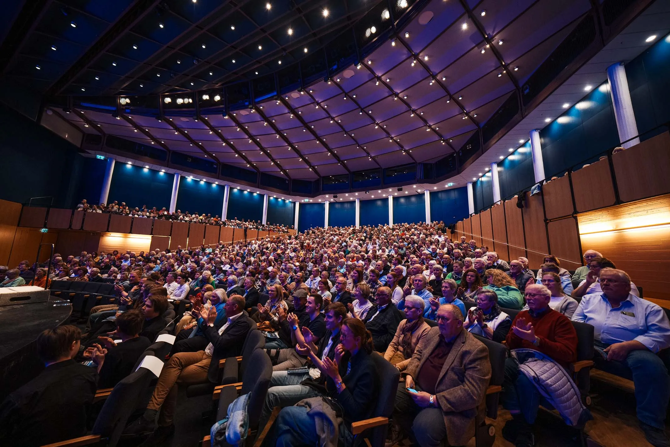 Ein großer Saal mit vielen Menschen besetzt. Alle warten, dass das Konzert startet.