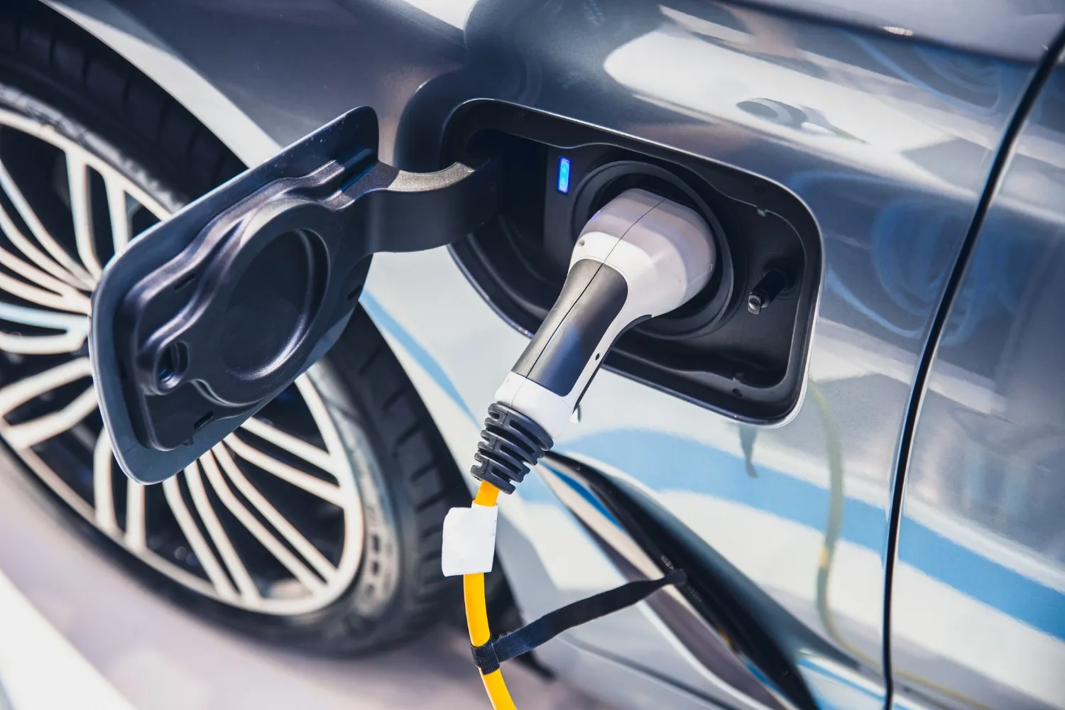 Close-up of an electric vehicle being charged with the connector plugged into the charging port.