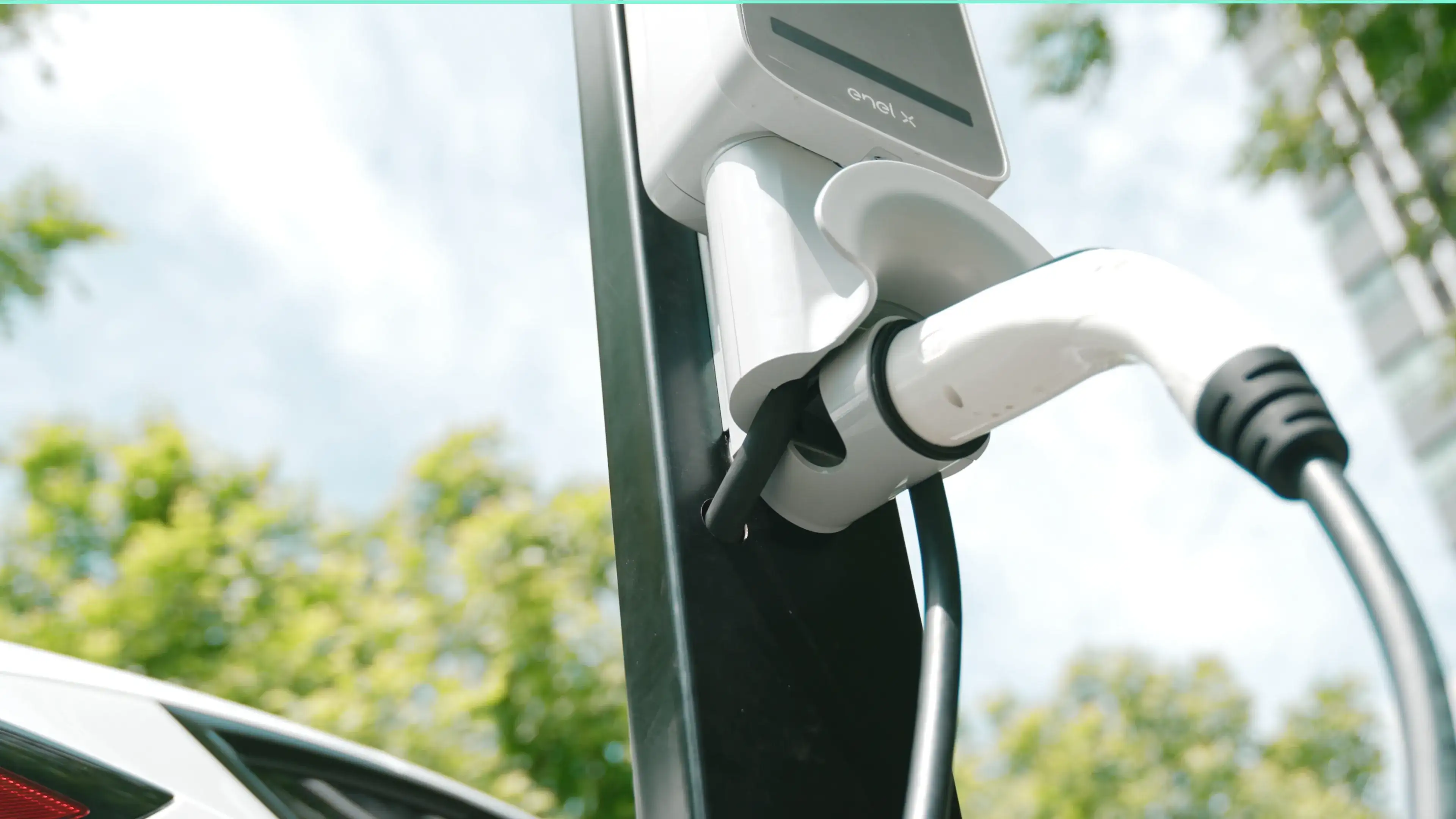 Close-up of a white EV charging cable handle plugged into an electric car.