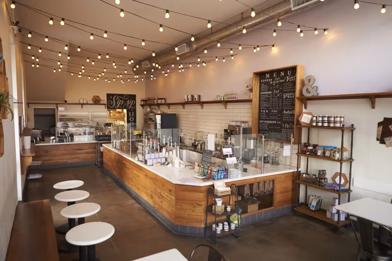 Intérieur d’un café artisanal en Alsace, avec comptoir en bois, guirlandes lumineuses et ambiance chaleureuse.