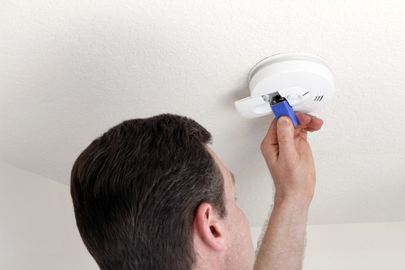 Technicien installant une centrale de détection incendie sur un mur dans un local professionnel