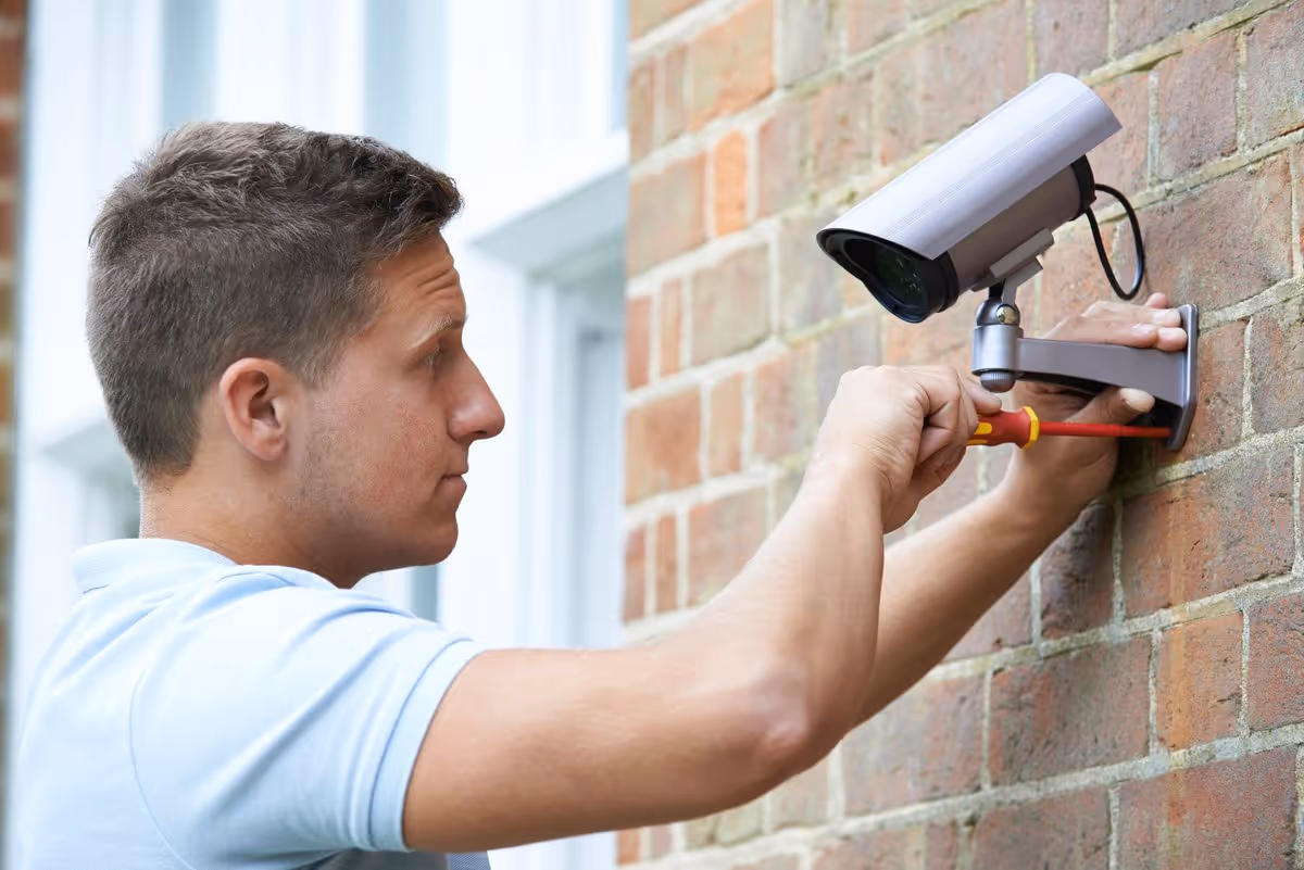 Technicien installant une caméra de vidéosurveillance sur le mur extérieur d’une copropriété à Strasbourg