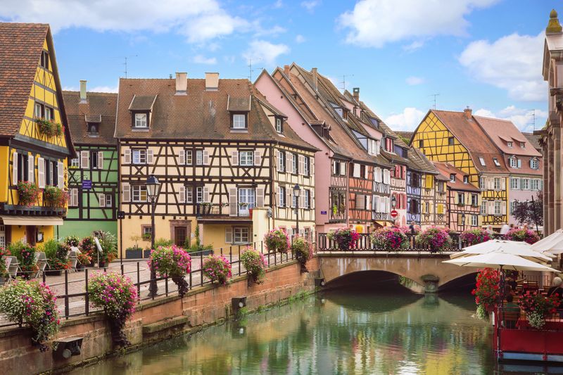 Maisons alsaciennes traditionnelles et canal fleuri dans le quartier de la Petite Venise à Colmar.