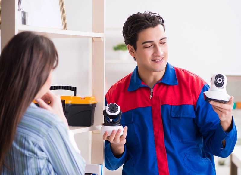 Technicien présentant des caméras de surveillance à une cliente