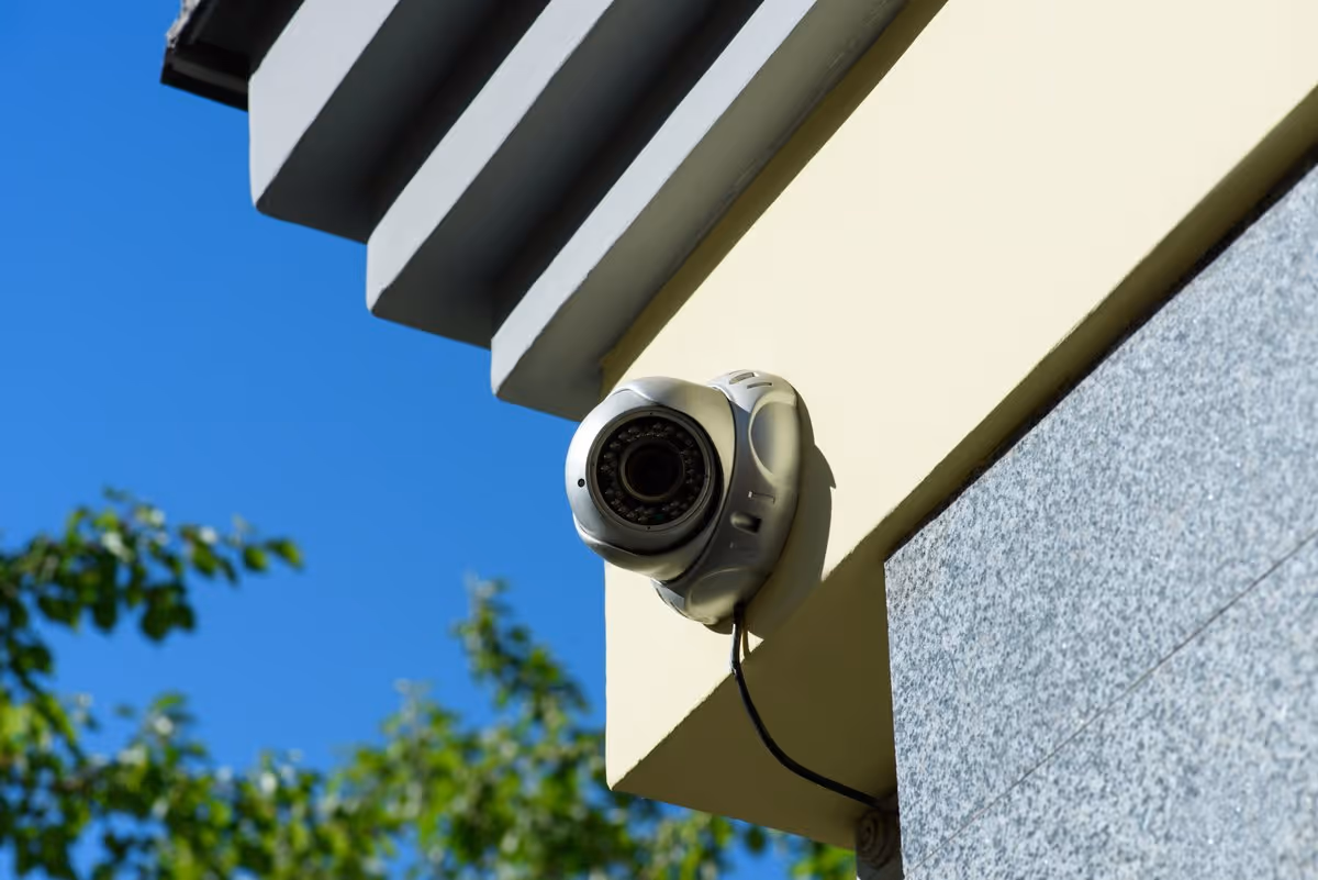 Caméra de vidéosurveillance extérieure fixée sur la façade d’une maison moderne à Sélestat sous un ciel bleu.