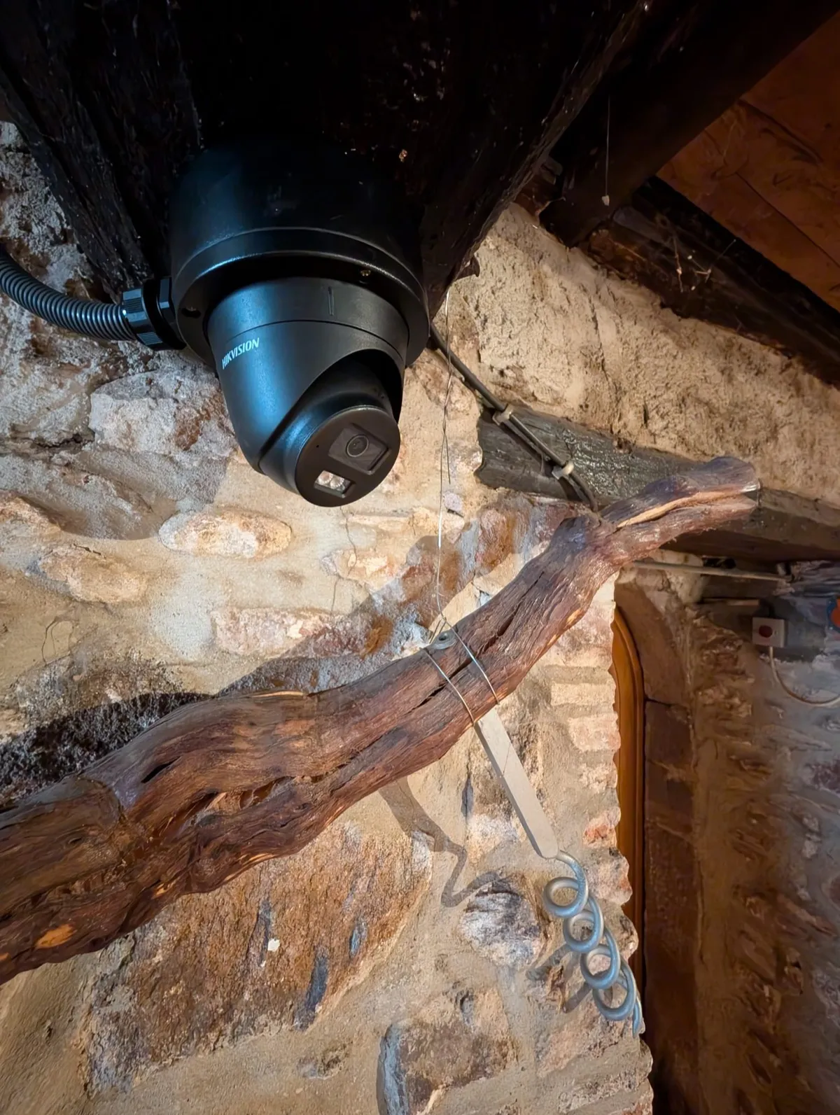 Caméra Hikvision fixée près d’une poutre ancienne dans un caveau viticole à Kaysersberg