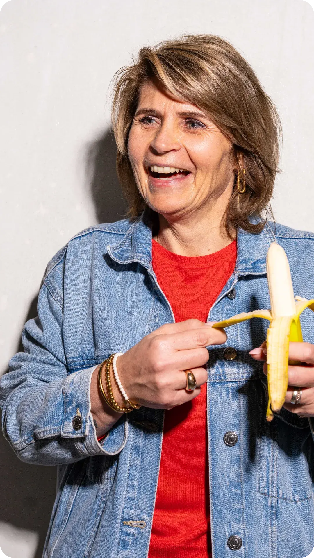 Een medewerker eet lachend een banaan uit de fruitkrat van Froot, bevordert vitaliteit en werkgeluk.