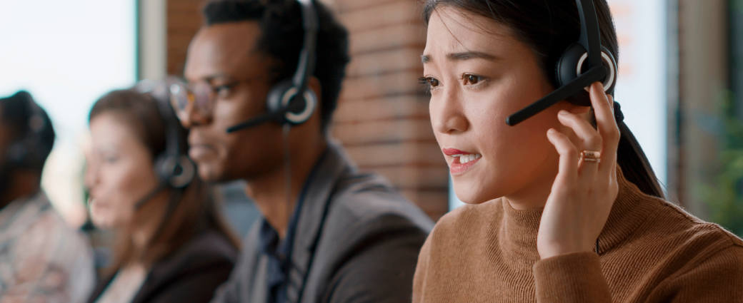 Female customer service agent with a headset gives assistance at a call center work station
