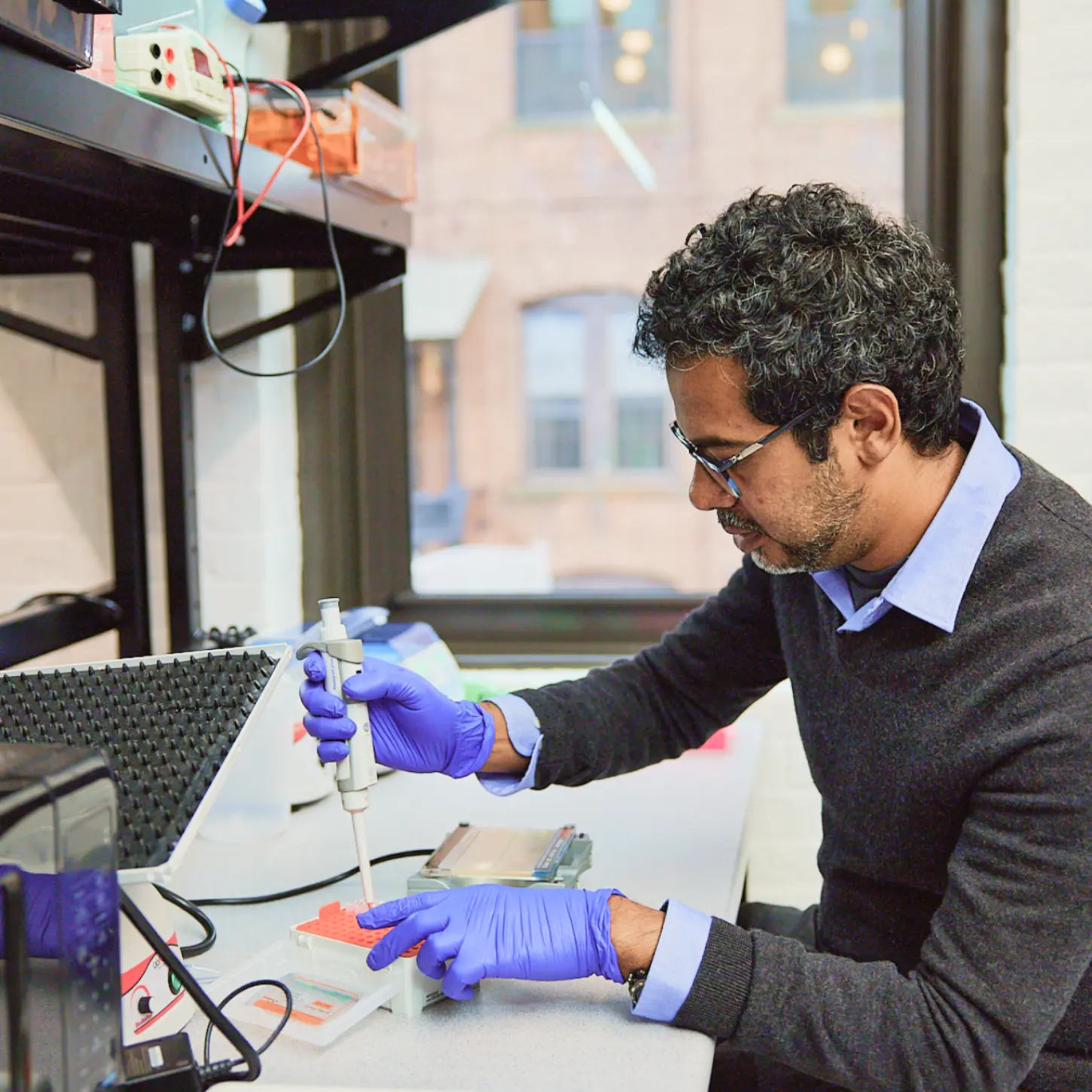 a person wearing gloves and using a pipette in a lab
