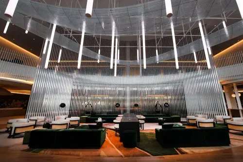 A circular room with couches, tables, and chandeliers.