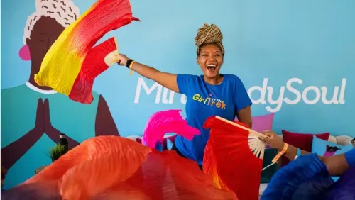 A woman in a blue shirt and a bunch of colorful umbrellas.
