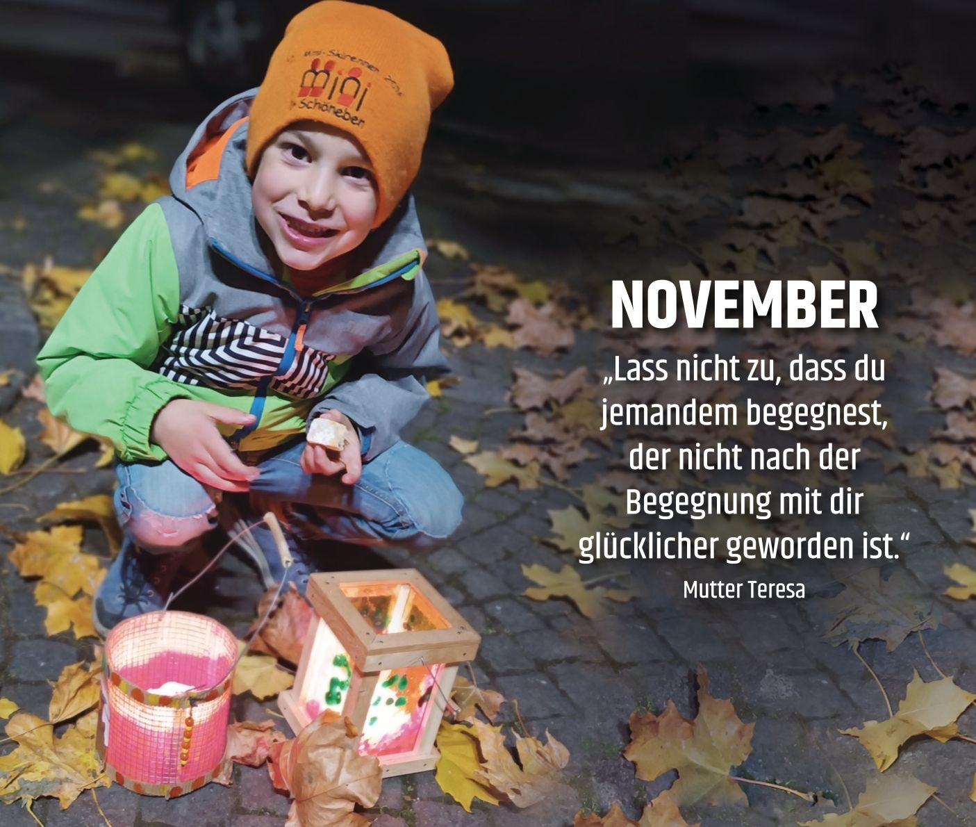 Ein Junge mit Mütze beim Martinsumzug mit seinen beiden Laternen auf der Straße, die mit Herbstlaub bedeckt ist.