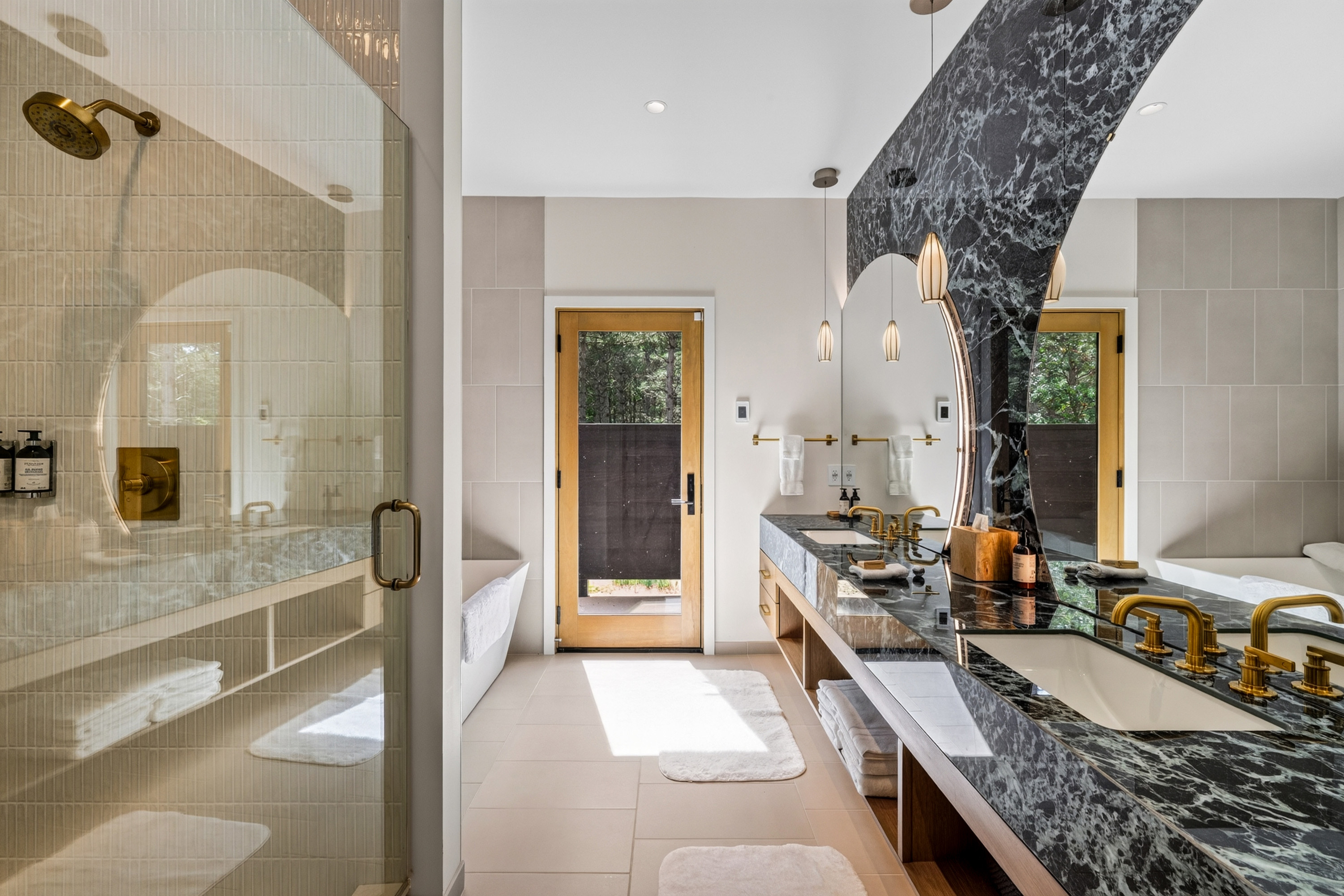 Bathroom with glass shower, black marble vanity, gold fixtures, and large mirror.