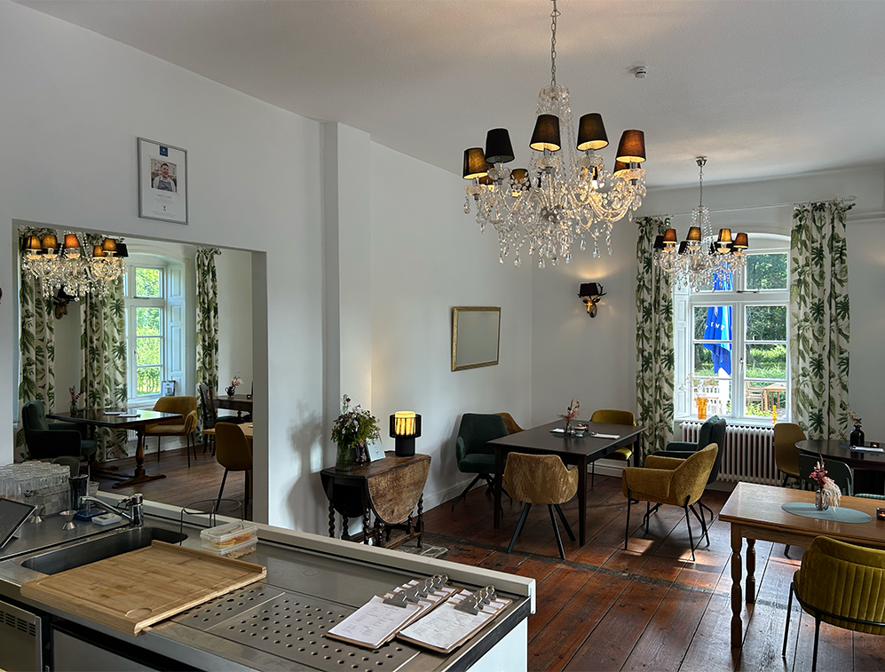 Innenbereich des Café Alte Schule by Erna in Wulfshagen, Tüttendorf. Sitzmöglichkeiten mit Stil. Kronenleuchter, alte Holztische.