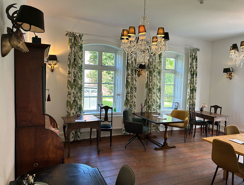 Der Innenbereich des Café Alte Schule by Erna in Wulfshagen Tüttendorf. Elegante Deckenlampen, alte Holztische, nette Sitzgelegenheiten. 