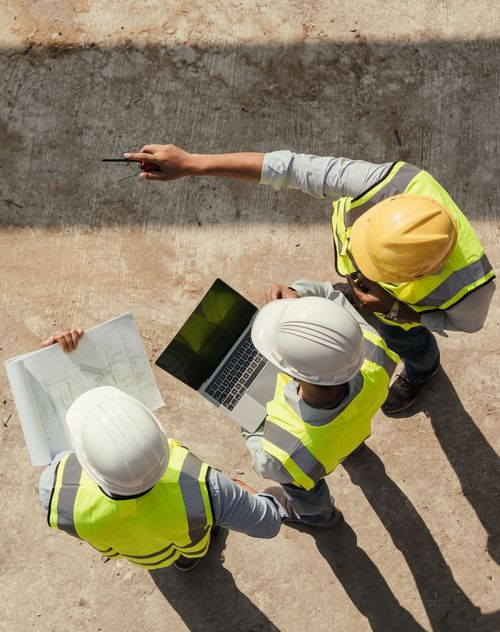 An top down image of three tradesmen discussing plans