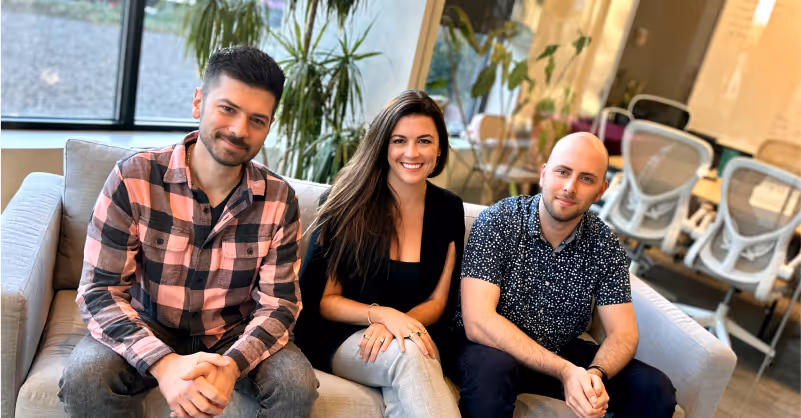 Three professionals sitting on a couch in a office, marking Spekit's acquisition of Cquence to advance AI sales enablement