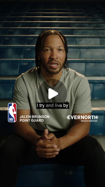 Jalen Brunson seated in empty arena seating in a grey T-shirt, with NBA and Evernorth Health Services logos, captioned: I try and live by.