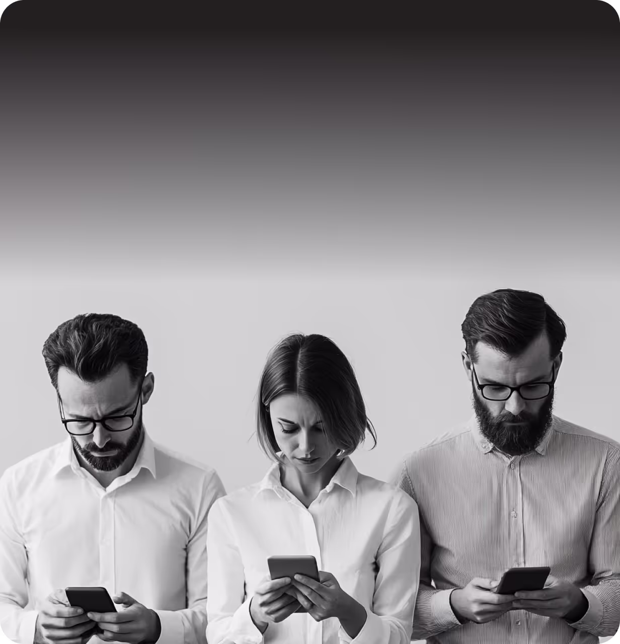 Black and white photo of three professionally dressed individuals, two men and one woman, standing in a row, each focused on their smartphone, symbolizing digital engagement or technological dependency.