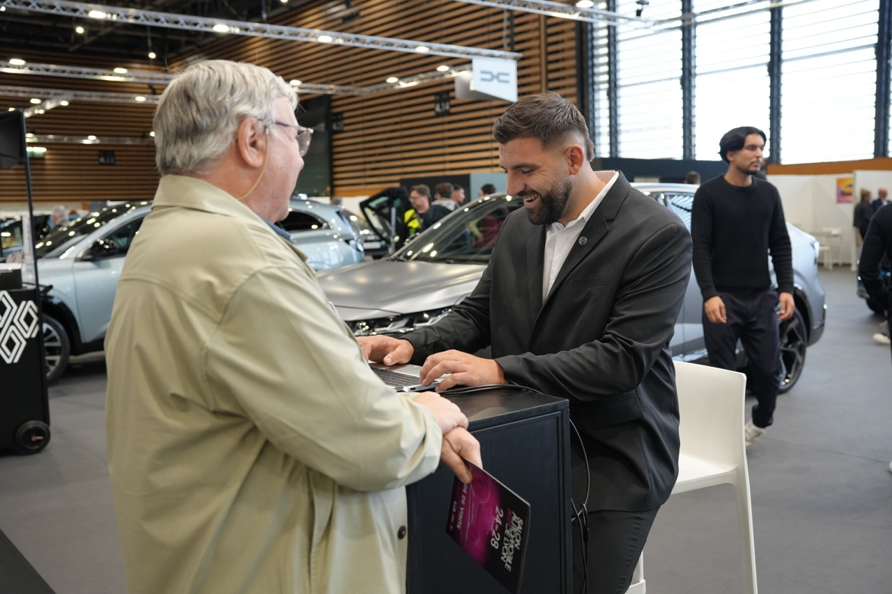 Hôte gérant l'accueil d'un visiteur et la prise de renseignements sur un stand automobile