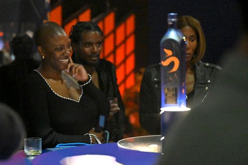 Des gens regardent une bouteille de whisky placée au centre d'une table.