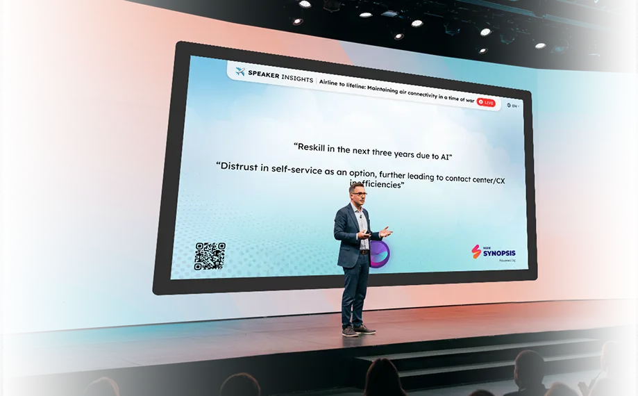 Man in a suit giving a presentation on stage in front of a large screen showing airline industry insights about AI reskilling and customer service distrust.