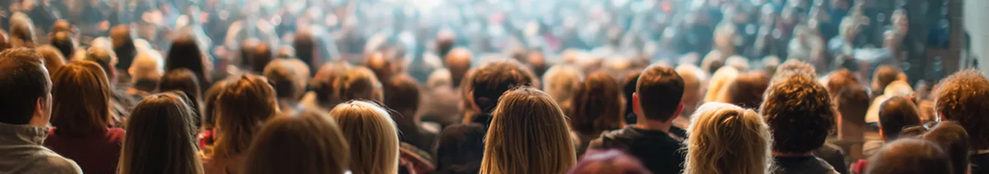 Large crowd of people sitting and facing forward in a conference or event setting.