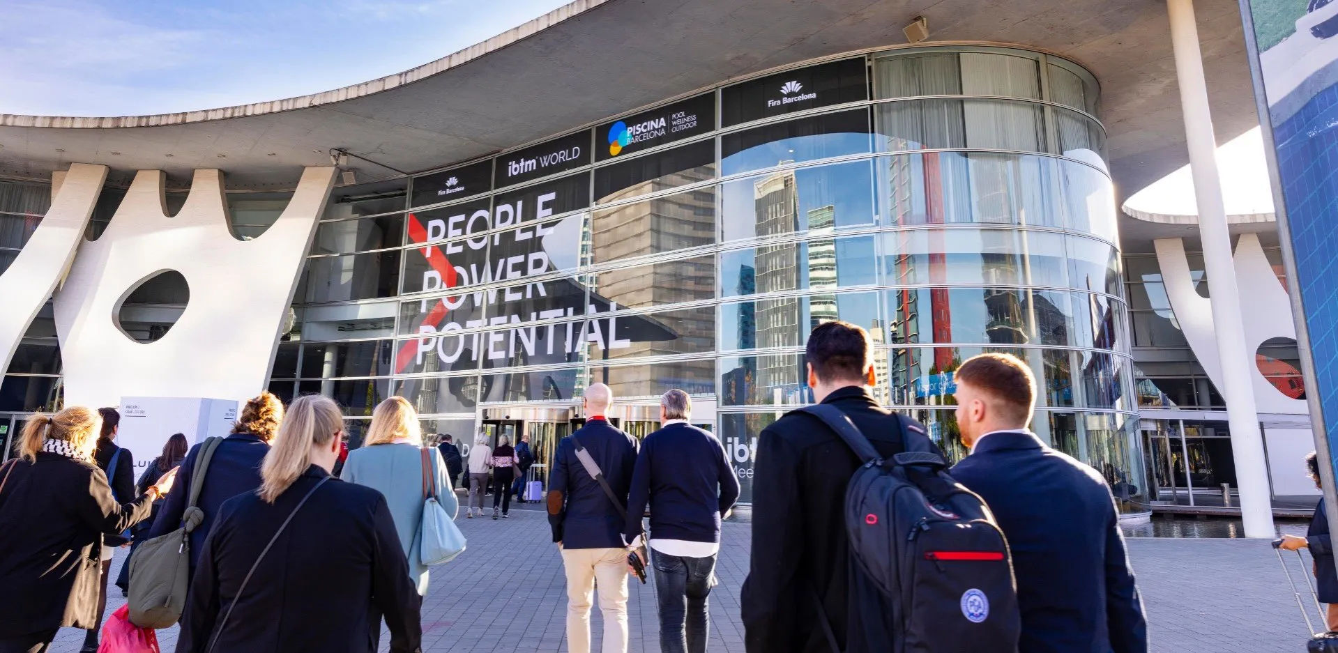 People walking toward a modern glass building with a sign that reads People Power Potential.