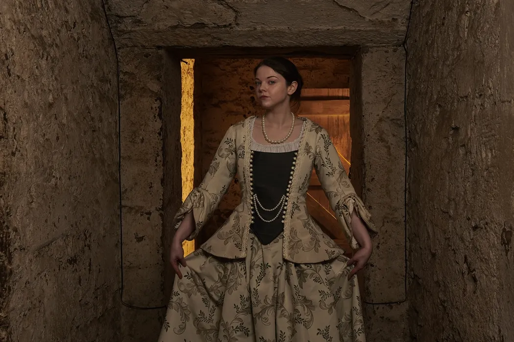 Real Mary King's Close tour guide in period costume in preserved 17th century tunnel.