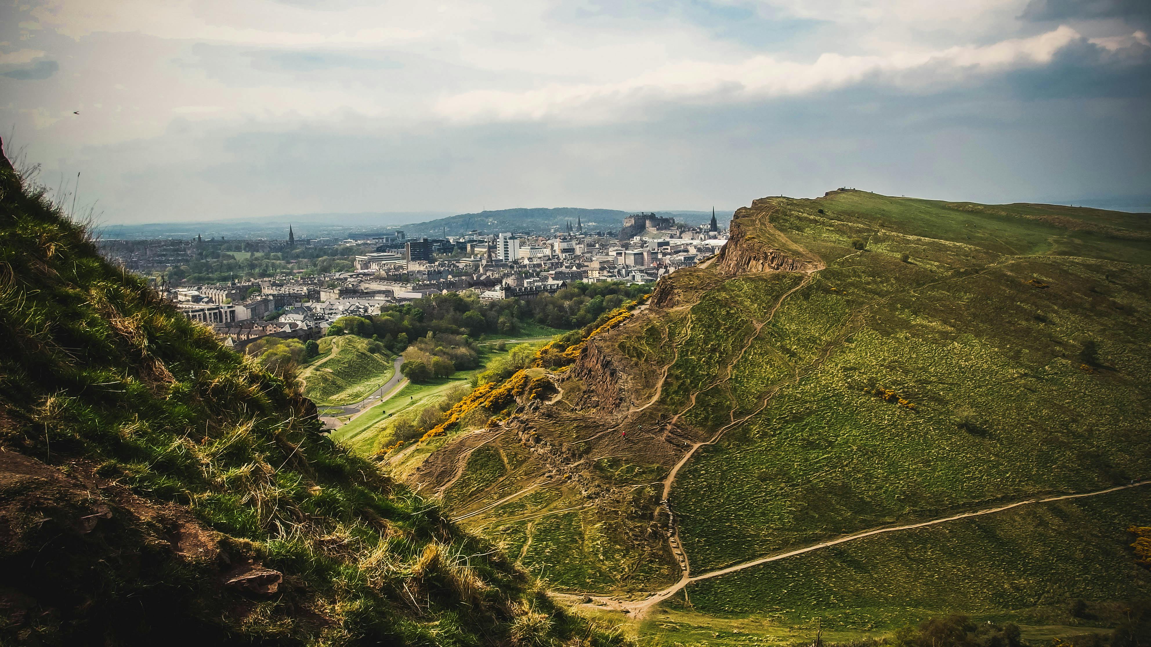 Edinburgh city skyline view from Arthur's Seat showing castle and historic buildings.