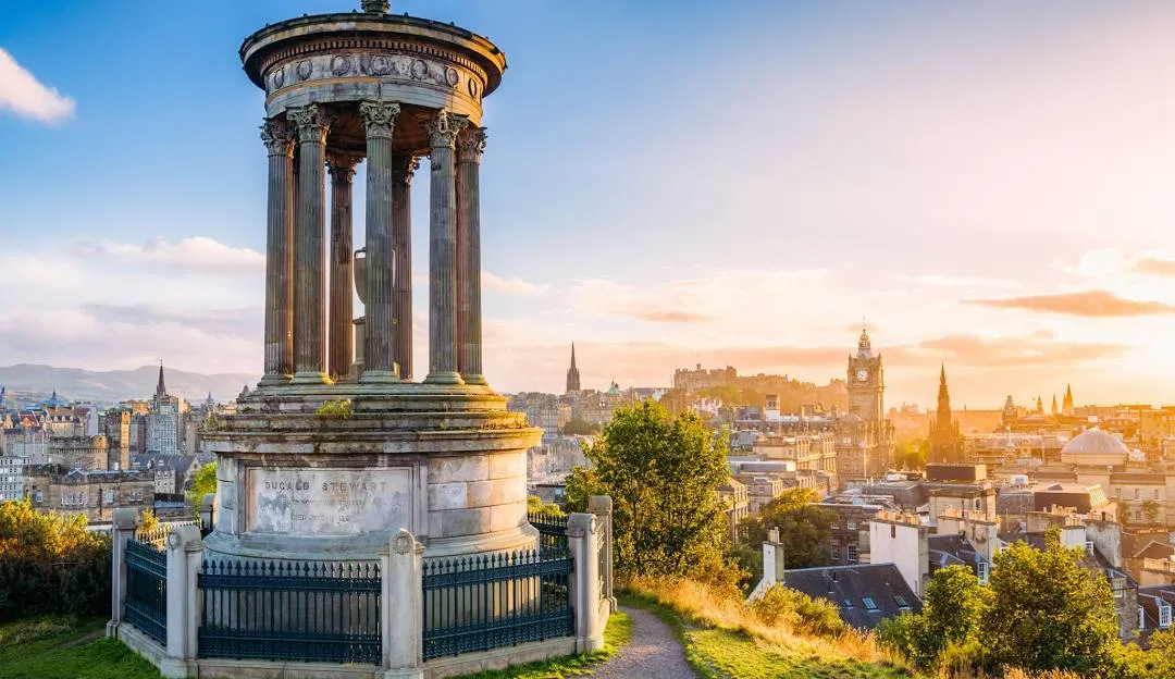 Calton Hill monument at sunset with Edinburgh castle views in background.