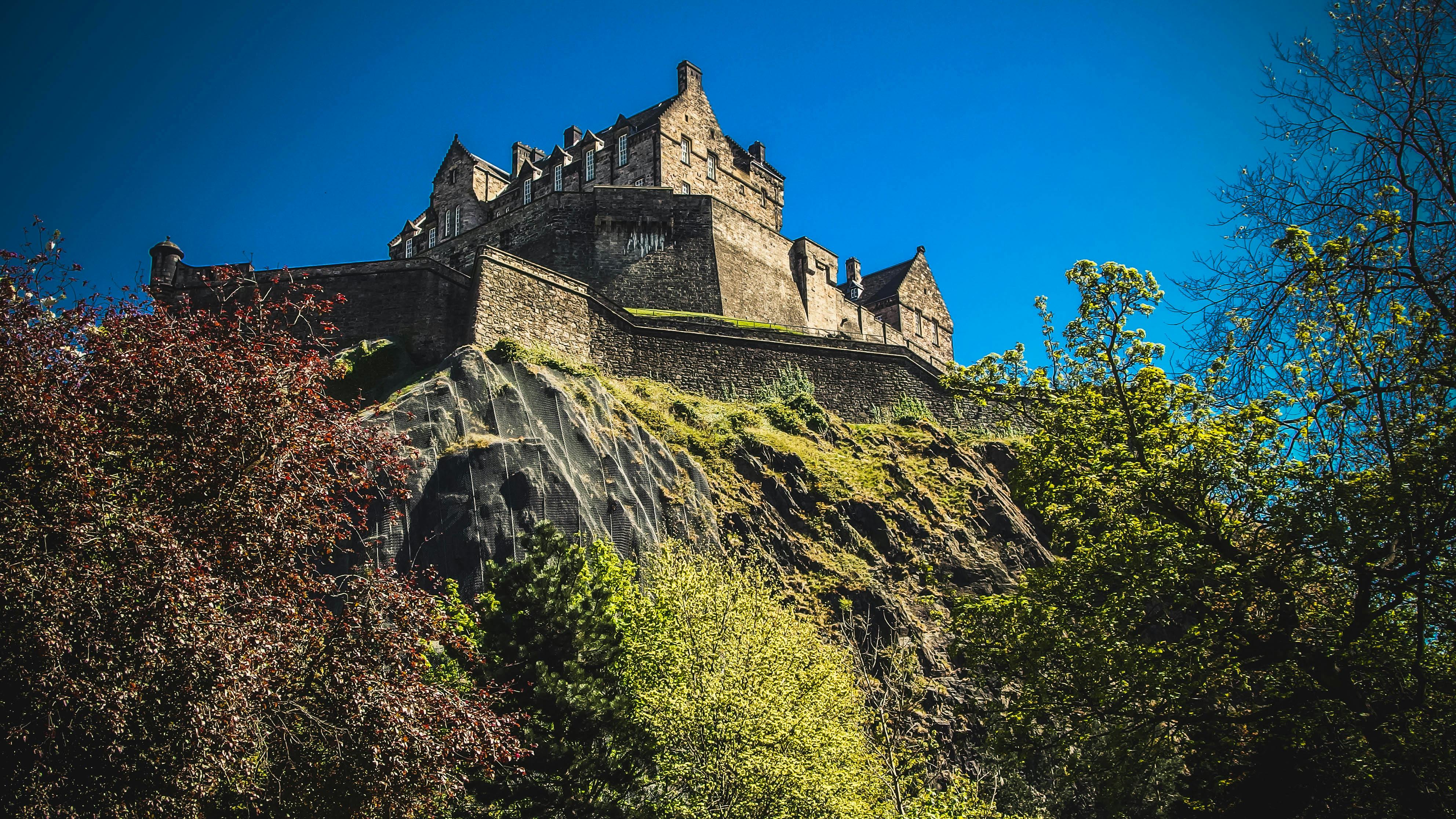 Edinburgh Castle perched on volcanic rock with autumn foliage - iconic Scottish landmark and top tourist attraction.