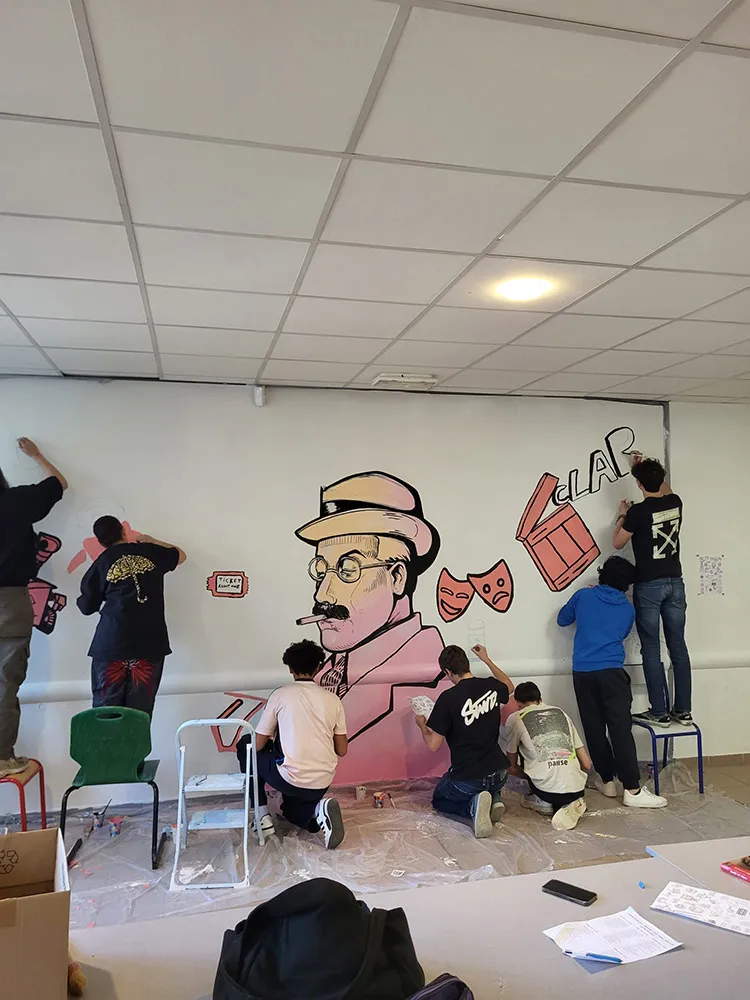 Élèves appliquant les touches finales sur une fresque représentant un personnage au style rétro entouré d’éléments liés au septième art.